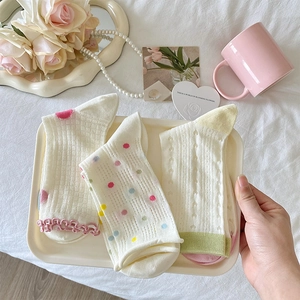 Detailed view of three pairs of pastel cotton socks with ruffles, dots, and heart patterns