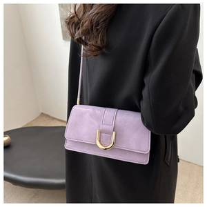Detail of lavender lilac crossbody bag with golden horseshoe buckle on black blazer