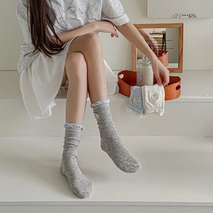 Detail of grey, blue, and white socks with cartoon dog embroidery and frill lace cuffs