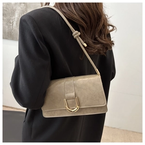 Detail of khaki green matte shoulder bag with gold U-shaped lock on a black suit model