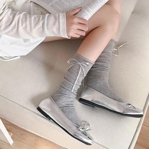 Detail of silver ballet flats with gray slouch socks featuring satin bow accents