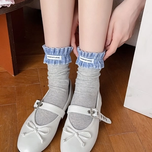Detail of grey ribbed socks featuring blue plaid ruffle cuffs and a brand label
