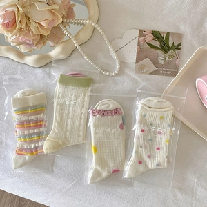 Detail of four pairs of cream socks with pastel patterns in neat transparent packaging