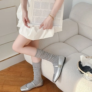 Detail of silver Mary Jane flats with grey knit socks showing the retro square toe design