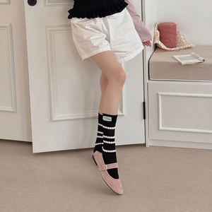 Detail of black polka dot socks with fabric label paired with pink suede Mary Janes