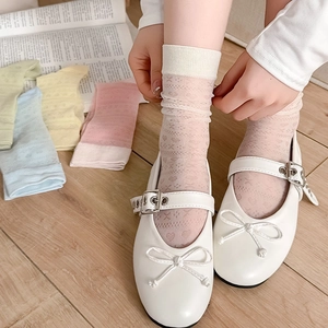 Close-up of sheer mesh socks with heart patterns and Mary Jane shoes in soft pastel tones