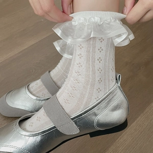 Gros plan de chaussettes Lolita en dentelle blanche avec maille fleurie et volants délicats