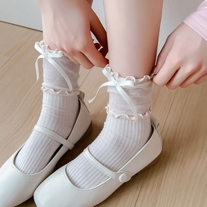 Close-up of white ballet style mesh socks with silk ribbons and wavy ruffled edges