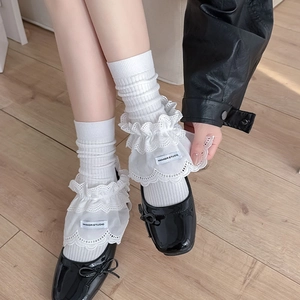 Detailed view of white ruffled leg warmers with lace trim and Mary Jane shoes