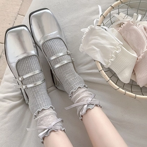 Detail of ballet style bow socks with ruffled edges worn with silver Mary Jane shoes