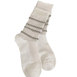 White crew socks for women featuring ruffle cuffs, grey polka dot stripes, and lace labels