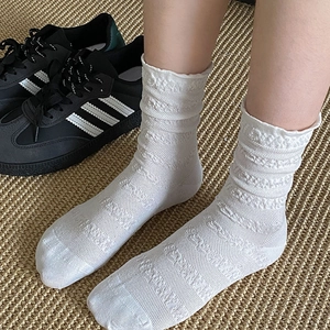 Gros plan de chaussettes blanches en dentelle avec motifs floraux et bords ondulés doux