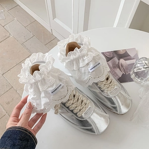 Detailed close-up of silver lace sneakers with layered white lace ruffles and bow details