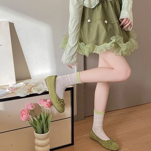 Detail of light green suede ballet flats with bow and white lace heart hollow socks