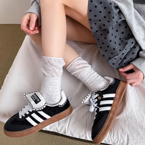 Gray mesh knit socks paired with black classic leather sneakers and brown rubber soles