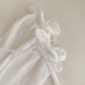 Detail of white knit socks with sheer texture, ruffle trim, and a delicate sweet bow