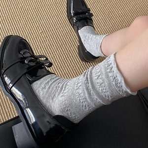 Détail de chaussettes grises à côtes avec mocassins en cuir verni noir à nœud