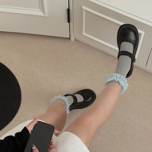 Détail de chaussettes grises à côtes avec dentelle bleu clair et Mary Janes noires