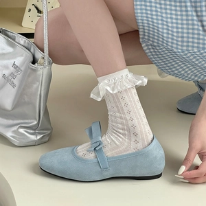 Detail of light blue Mary Jane shoes with floral embroidery lace socks and a silver handbag