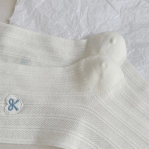 Macro detail of breathable white mesh socks with heart and blue bow embroidery