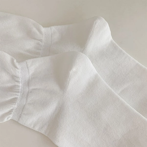 Macro shot of white knitted slouch socks showing fine texture and elastic fabric detail
