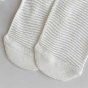 Close-up of white ribbed knit cotton socks showing smooth toe stitching and fine texture