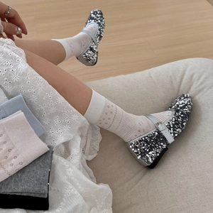 Close-up of silver sequin Mary Jane shoes with hollow floral pattern white cotton socks