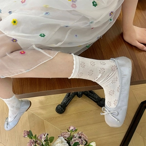 Detail of white mesh socks with floral embroidery and satin ballet flats with bows