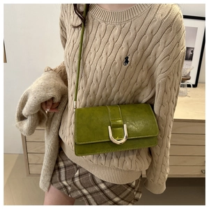 Close-up of Matcha green leather crossbody bag with elegant gold U-shaped metal lock