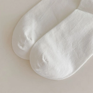 Close-up of white knit socks featuring fine texture and smooth flat-seam toe stitching