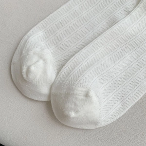 Detail of white mesh knit socks featuring breathable hollow patterns and ribbed texture