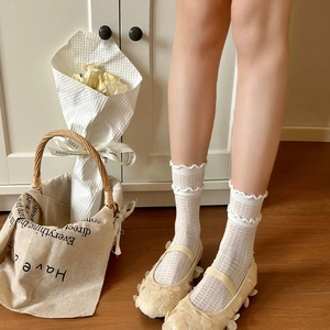 Detail of white mesh lace socks paired with sequined ballet flats in a cozy home setting