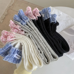 Close-up of ribbed knit crew socks with colorful plaid ruffle cuffs and logo tags