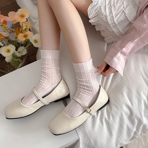 Vertical mesh socks in white styled with cream Mary Jane flats in a cozy home setting