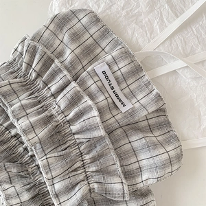 Macro detail of black and white checkered fabric with ruffled lace and brand woven label