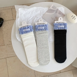 Flat lay of ribbed crew socks in white grey black with blue checkered frill edges