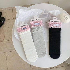 Detailed view of women's mid-tube socks with pink plaid ruffle trim and ribbed texture