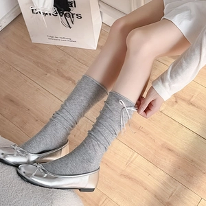 Detail of grey knitted calf socks with silver ribbon bows paired with silver ballet flats