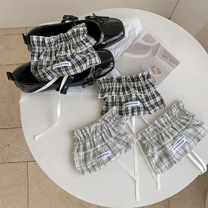 Detail of plaid balletcore leg warmers with ruffles, drawstrings and woven labels
