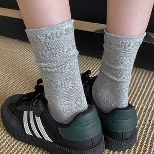 Gros plan de chaussettes grises à mi-mollet avec motifs de lettres et bord roulé