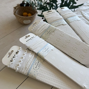Detail showing assorted white lace mesh socks with floral patterns and branded packaging