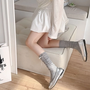 Close-up of grey slouch socks with white satin bows and silver ballet flats in balletcore style