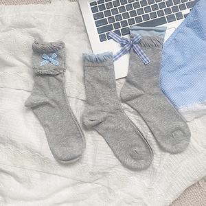 Detail of grey ruffled crew socks with blue checkered bows and textured patterns