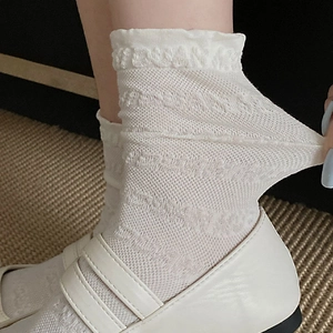 Gros plan de chaussettes en maille blanche respirante avec bords ondulés à volants