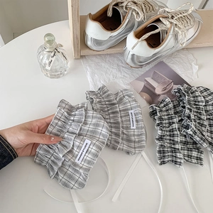 Detail of plaid ballet-style leg warmers with ribbons and delicate lace trim accents
