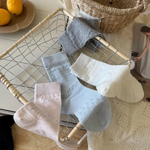 Detail of four-color pointelle cotton socks in a vintage metal basket display