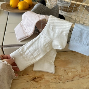 Detail of hollow out pattern socks in multiple colors hanging on a vintage iron basket