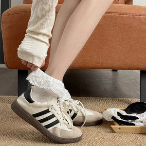Close-up of white Lolita lace socks with floral embroidery worn with retro sneakers
