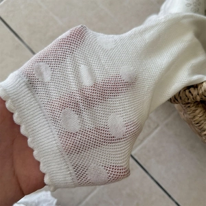 Macro shot of white mesh knit socks with polka dot pattern and scalloped wave edge