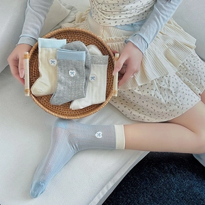 Close-up of ribbed knit socks with delicate embroidered bow details in pastel tones